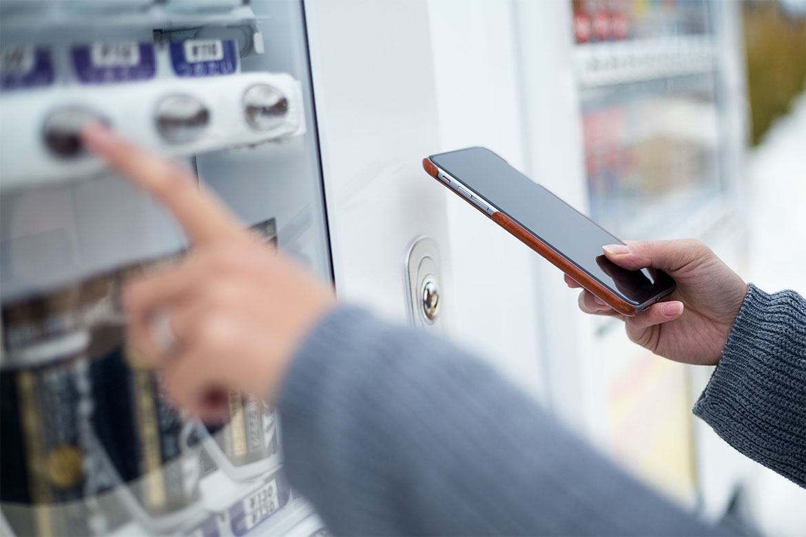 Woman using cellphone to pay the vending machine